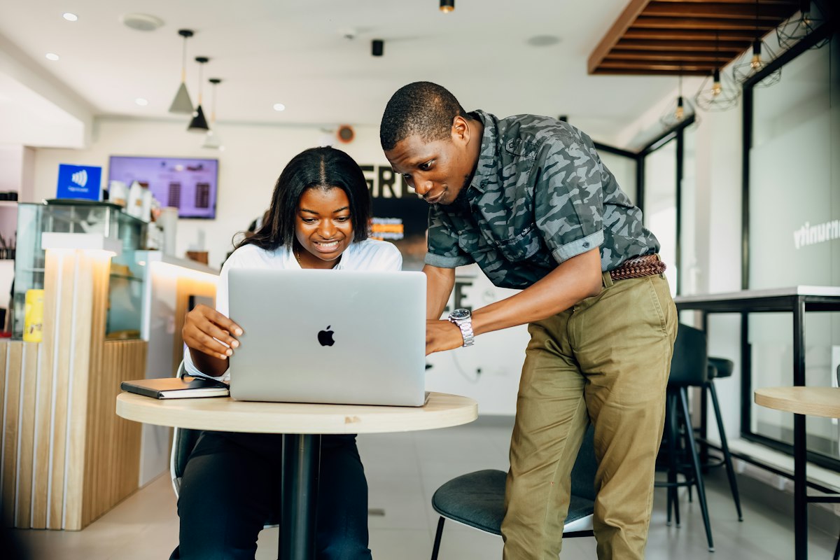 Two colleagues working together on a laptop in a cafe
