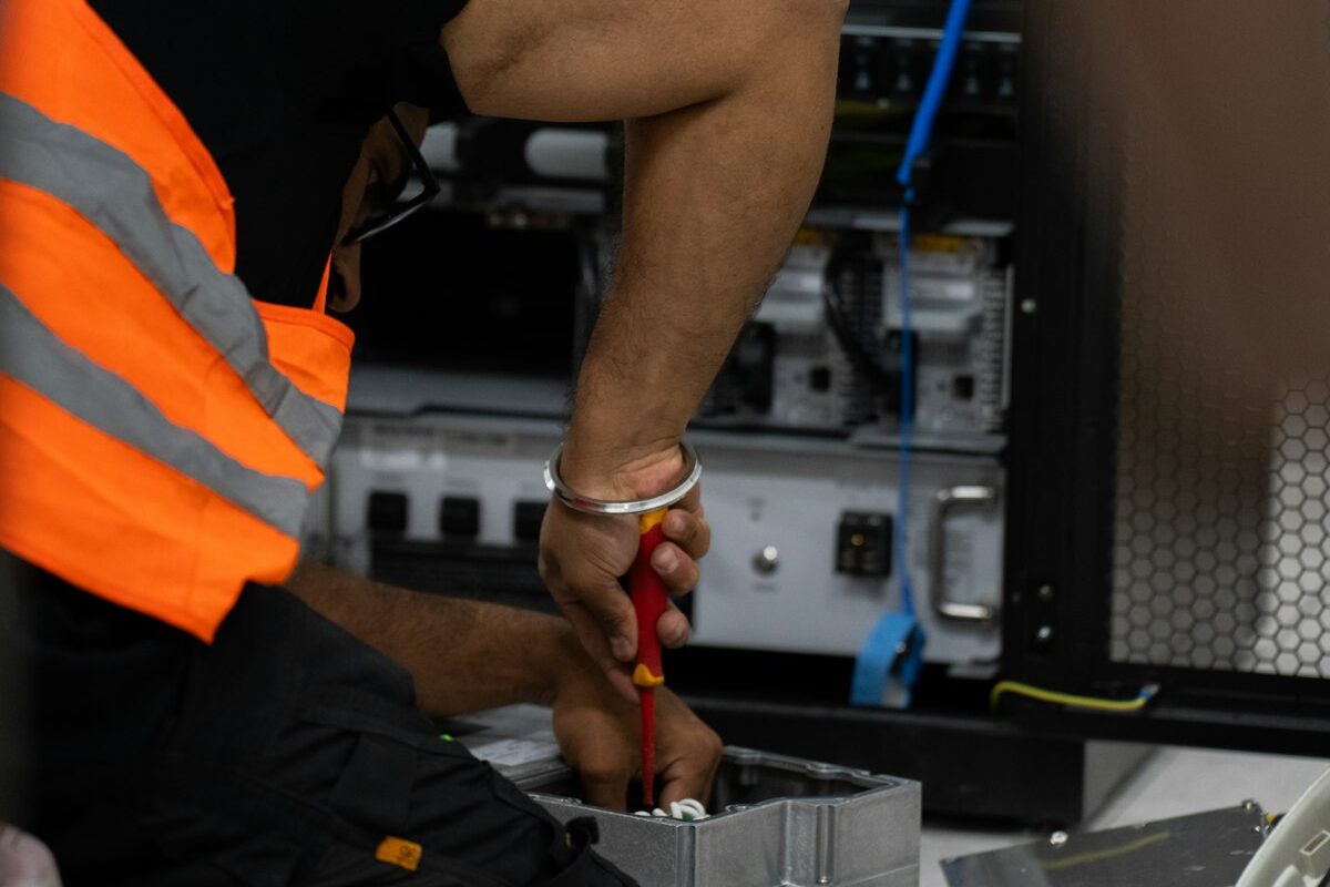A technician in a safety vest working on server equipment with tools