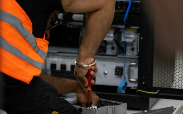 A technician in a safety vest working on server equipment with tools