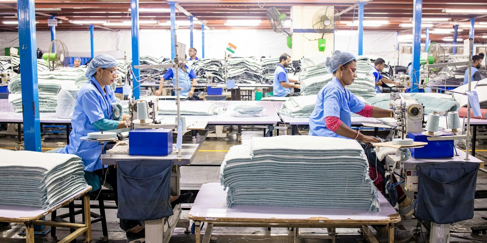 Workers sewing garments on a large textile manufacturing factory floor