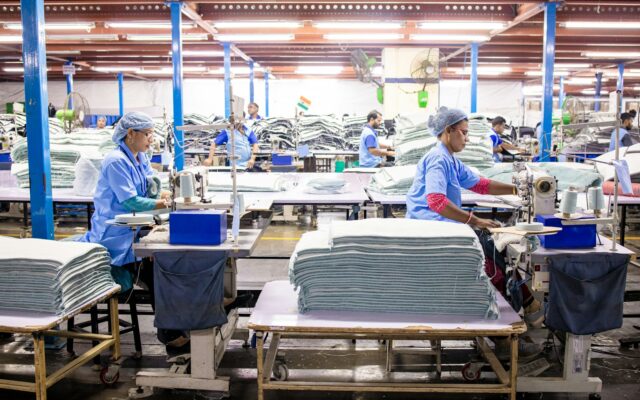 Workers sewing garments on a large textile manufacturing factory floor
