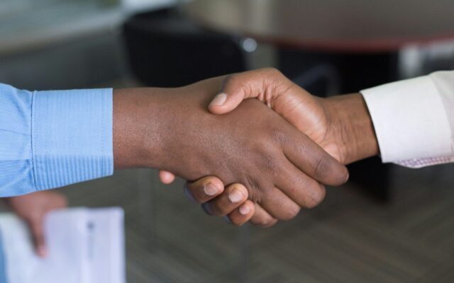 African business professionals shaking hands over a signed licensing and collaboration agreement