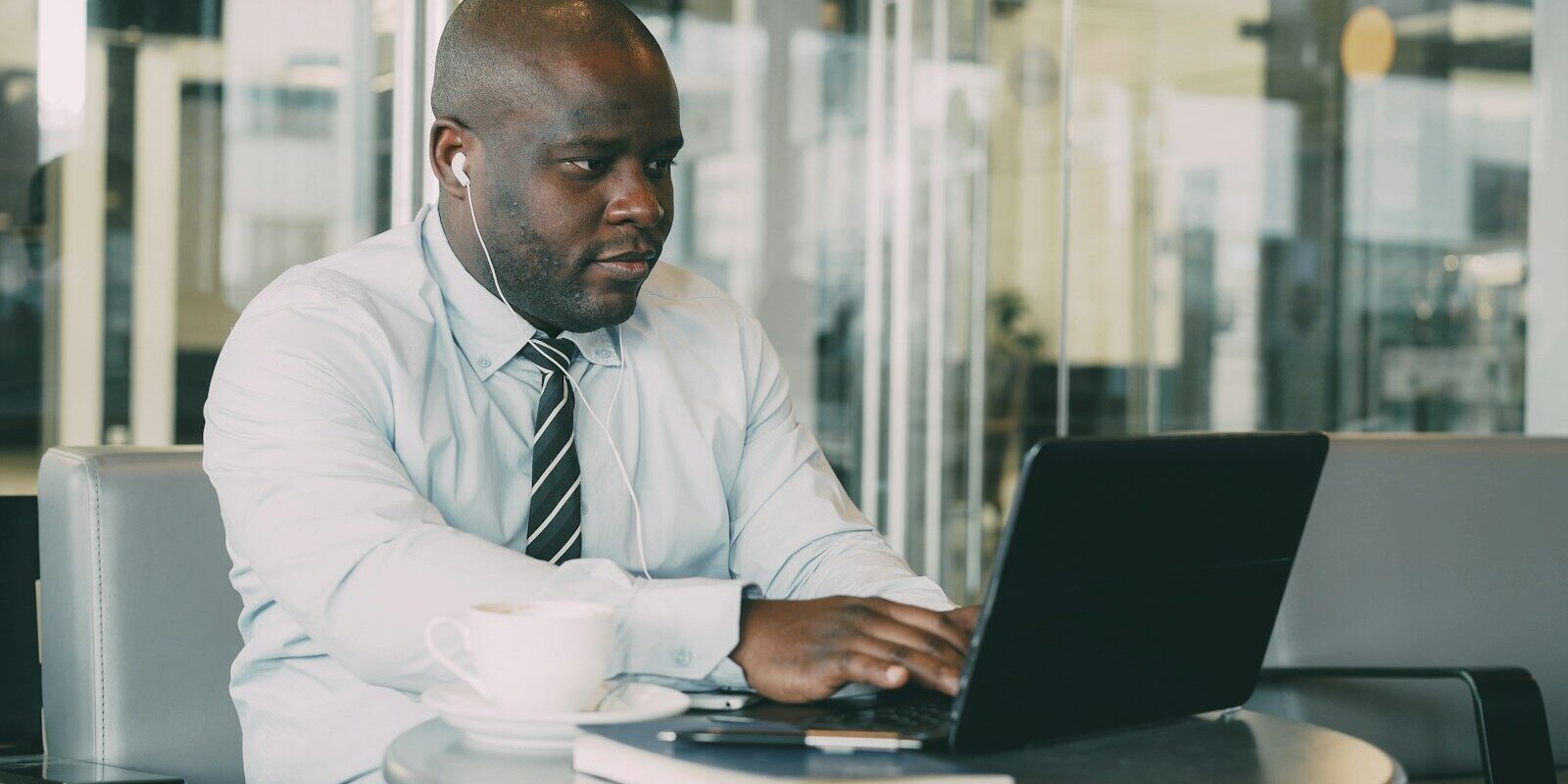 African businessman in a glass-walled office typing on a laptop, representing corporate compliance with cross-border data transfer rules in Kenya