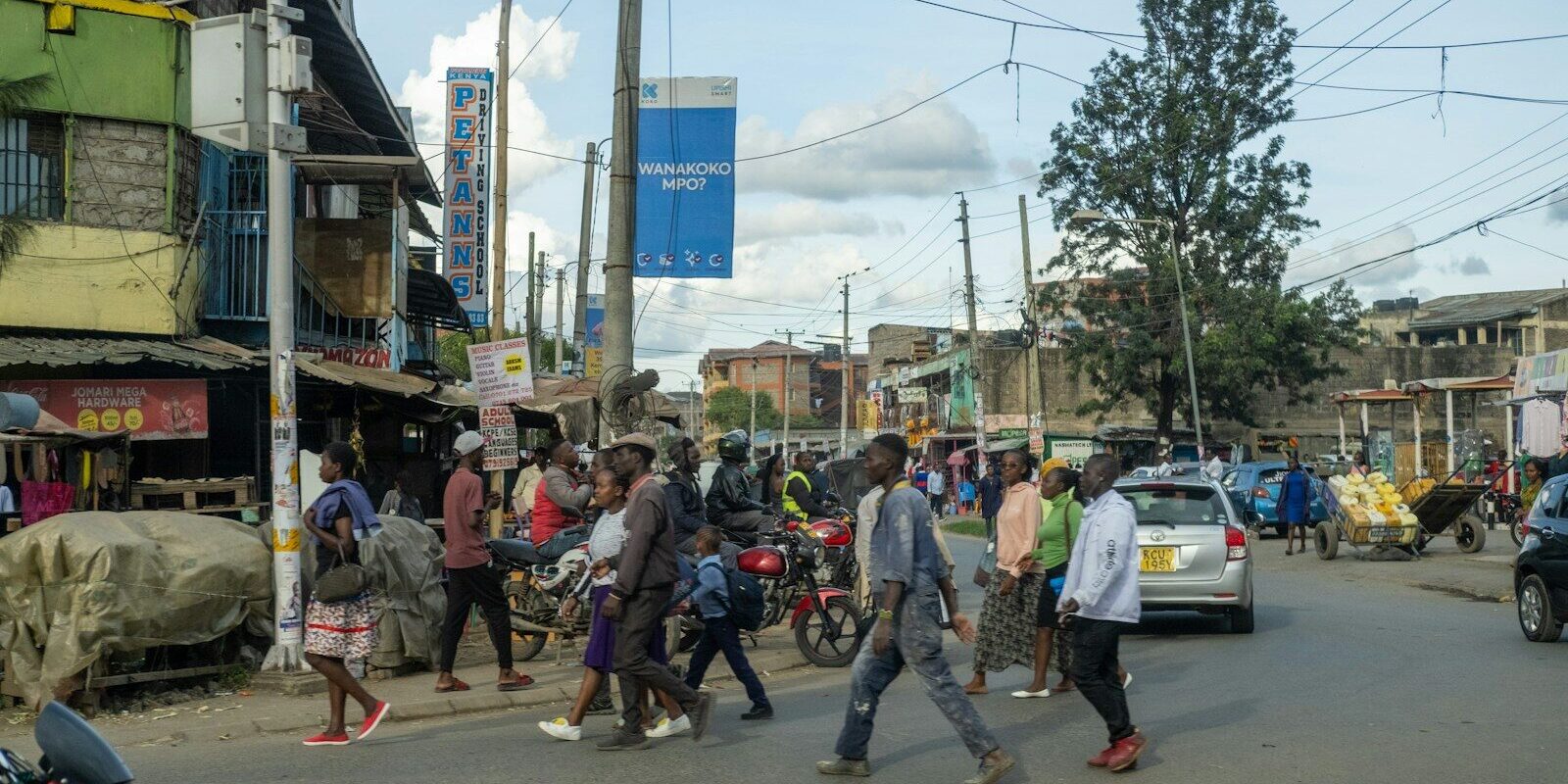 Pedestrians and motorbikes on a busy Kenyan street, illustrating life as a resident in Kenya for tax residence purposes