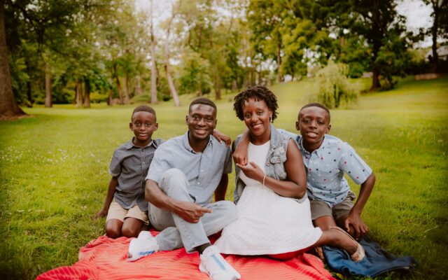 African parents and two sons seated together on a blanket in a park, illustrating dependants and family claims on an estate in Kenya