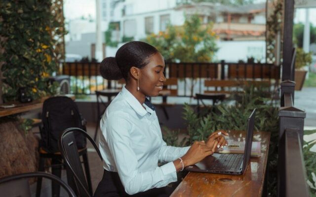 Woman working on a laptop at a cafe table, illustrating foreign employment income earned by a remote worker in Kenya