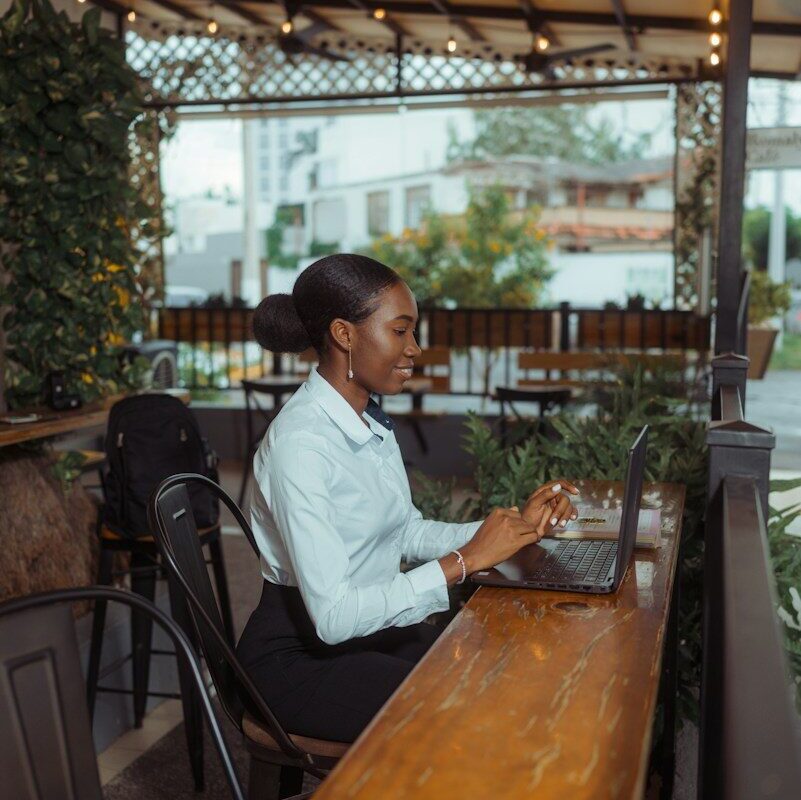 Woman working on a laptop at a cafe table, illustrating foreign employment income earned by a remote worker in Kenya