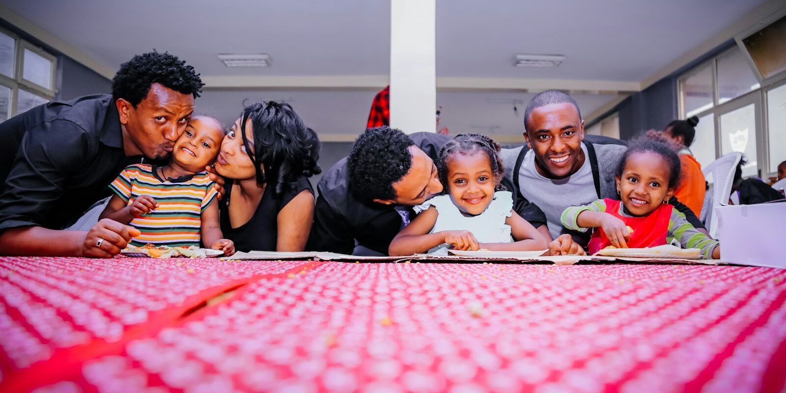 African parents and young children sharing a meal together at a table, illustrating appointing a guardian for minor children in Kenya