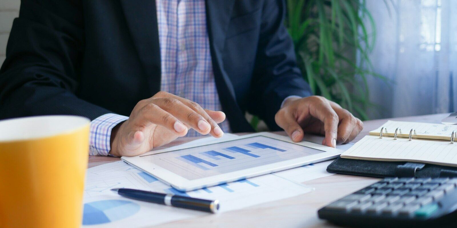 Professional in a dark suit reviewing financial charts on a tablet beside a calculator, illustrating foreign tax credit and deduction