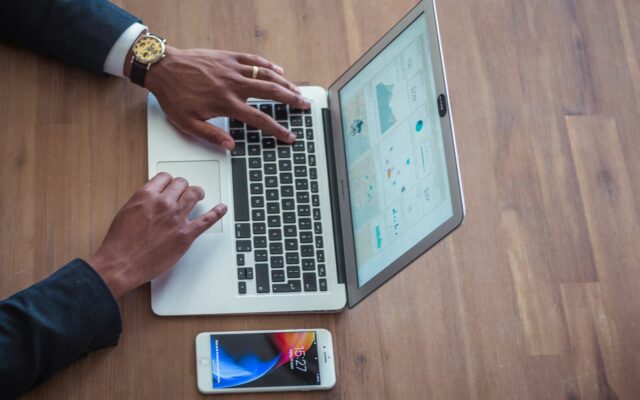 Hands typing on a laptop with a phone on the desk, illustrating an online Class N permit application