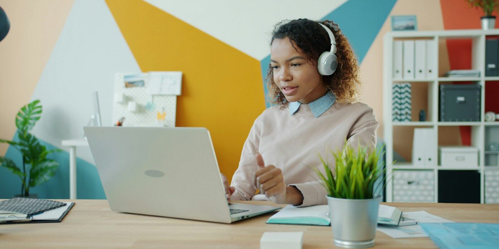 Woman wearing headphones on a video call at a laptop, illustrating a remote employee working from Kenya for a foreign employer