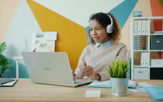 Woman wearing headphones on a video call at a laptop, illustrating a remote employee working from Kenya for a foreign employer