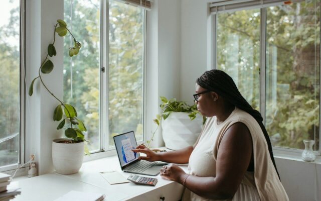 African woman working on a laptop beside a bright window, representing a remote worker on a Kenyan Class N permit